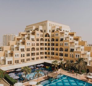 Aerial view of a modern architectural building in Dubai with a swimming pool in the foreground.