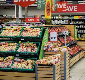 Colorful produce aisle in a supermarket showcasing fresh apples with discount signage.