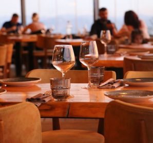 A warmly lit restaurant table set with glassware, plates, and napkins ready for a meal.