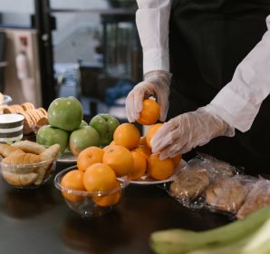 Caterer arranging fresh fruits and snacks on a table for a food service event.